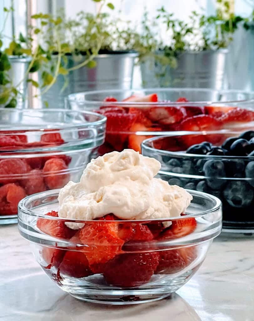 A bowl of fresh strawberries and homemade whipped cream with orange water