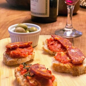 Toasted baguette with fresh tomato sauce sliced dry saucisson and French olives
