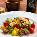 A plate with assorted charry tomatoes, fresh basil, homemade croutons and drizzeld with olive oil