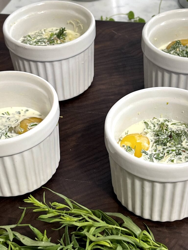 Eggs with herbs and cream in a ramekin ready to bake